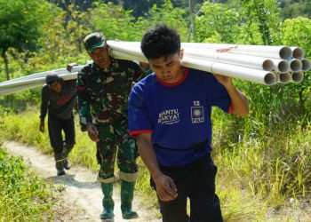 Gotong Royong Satgas TMMD Kodim 1401/Majene dan Warga Memanggul Pipa untuk Pipanisasi di Perbukitan