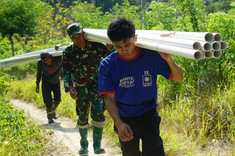 Gotong Royong Satgas TMMD Kodim 1401/Majene dan Warga Memanggul Pipa untuk Pipanisasi di Perbukitan