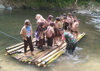 Babinsa di Polman Bantu Anak-Anak Sekolah Menyeberang Sungai dengan Rakit Bambu